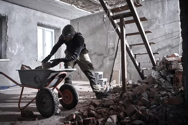 Man loading broken walls onto a wheelbarrow.