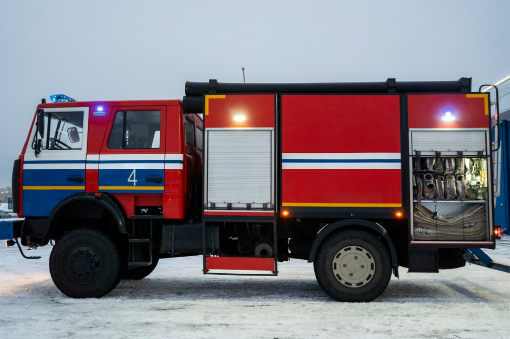 Modern red fire truck with equipment, parked on snowy ground