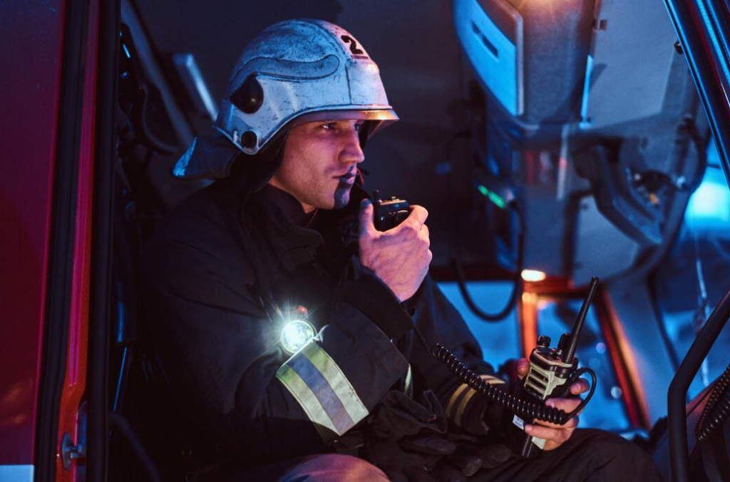 fireman in a protective uniform sitting in the fire truck and talking on the radio