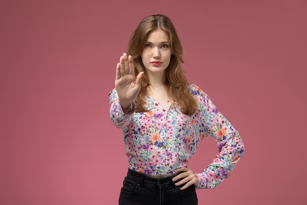 Woman in smart-casual attire gesturing to stop or signaling 'no'