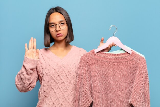 Woman holding knitted sweatshirts